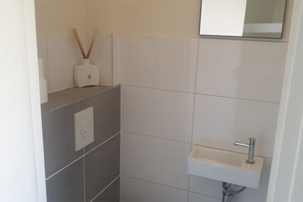 Toillet gerenoveerd, robuust beton met witte tegels