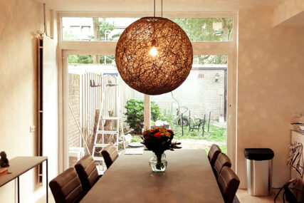 warme woonkamer met eettafel en rieten hanglamp